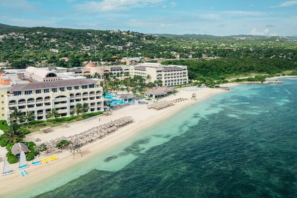 A resort with multiple buildings, a beach, and clear turquoise waters. - JOIA Rose Hall by Iberostar - Adults Only - All Inclusive (Montego Bay)