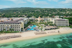Un resort con piscina central, varias edificaciones y una playa.
