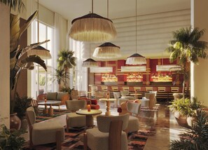 A spacious lobby with high ceilings, multiple seating areas, and a bar with a checkered red and yellow tile design.