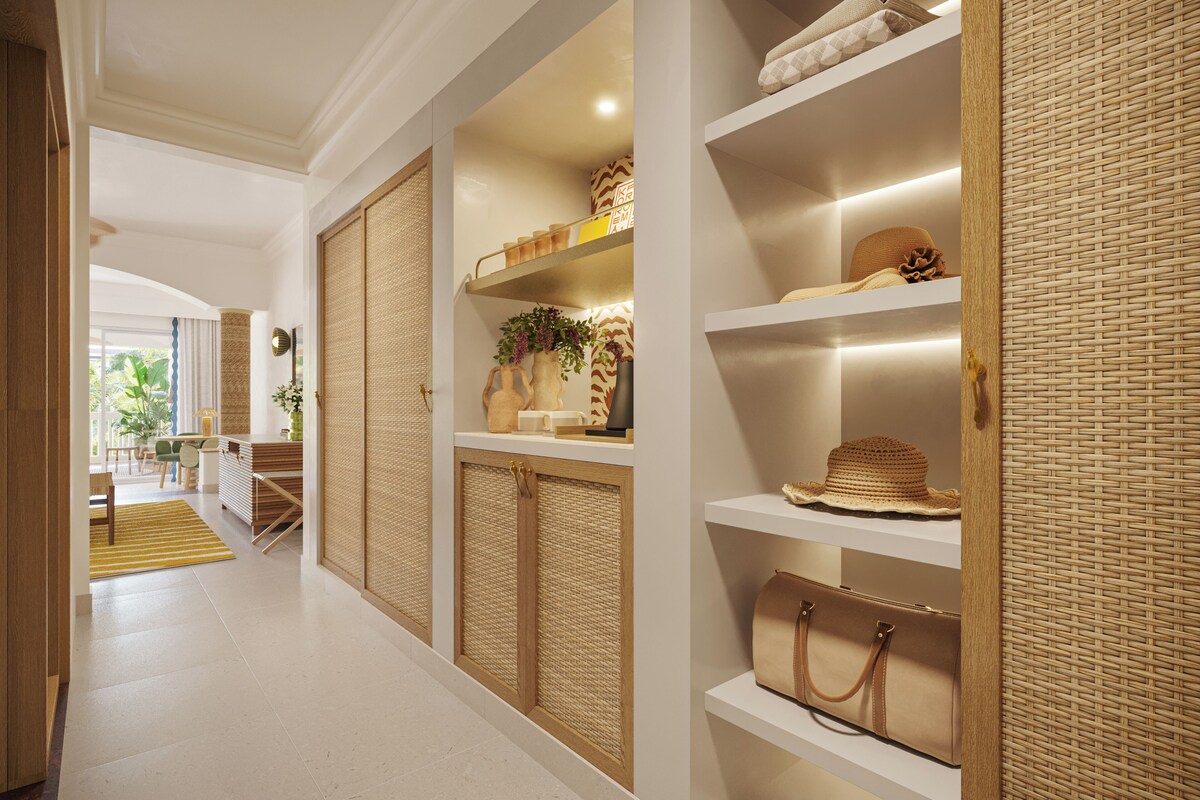 A hallway with a woven partition, shelves with bags, and a plant.