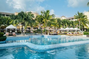 A resort pool area with a tiled edge, lounge chairs, umbrellas, and palm trees. - JOIA Rose Hall by Iberostar - Adults Only - All Inclusive (Montego Bay)