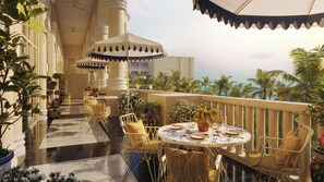A terrace with outdoor seating, a view of palm trees, and a building with classical architecture. - JOIA Rose Hall by Iberostar - Adults Only - All Inclusive (Montego Bay)