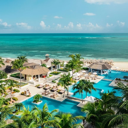 A resort with multiple swimming pools, palm trees, and a beach.