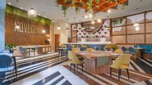 Een modern restaurant met een bakstenen muur, houten plafond en gestreept vloertje.