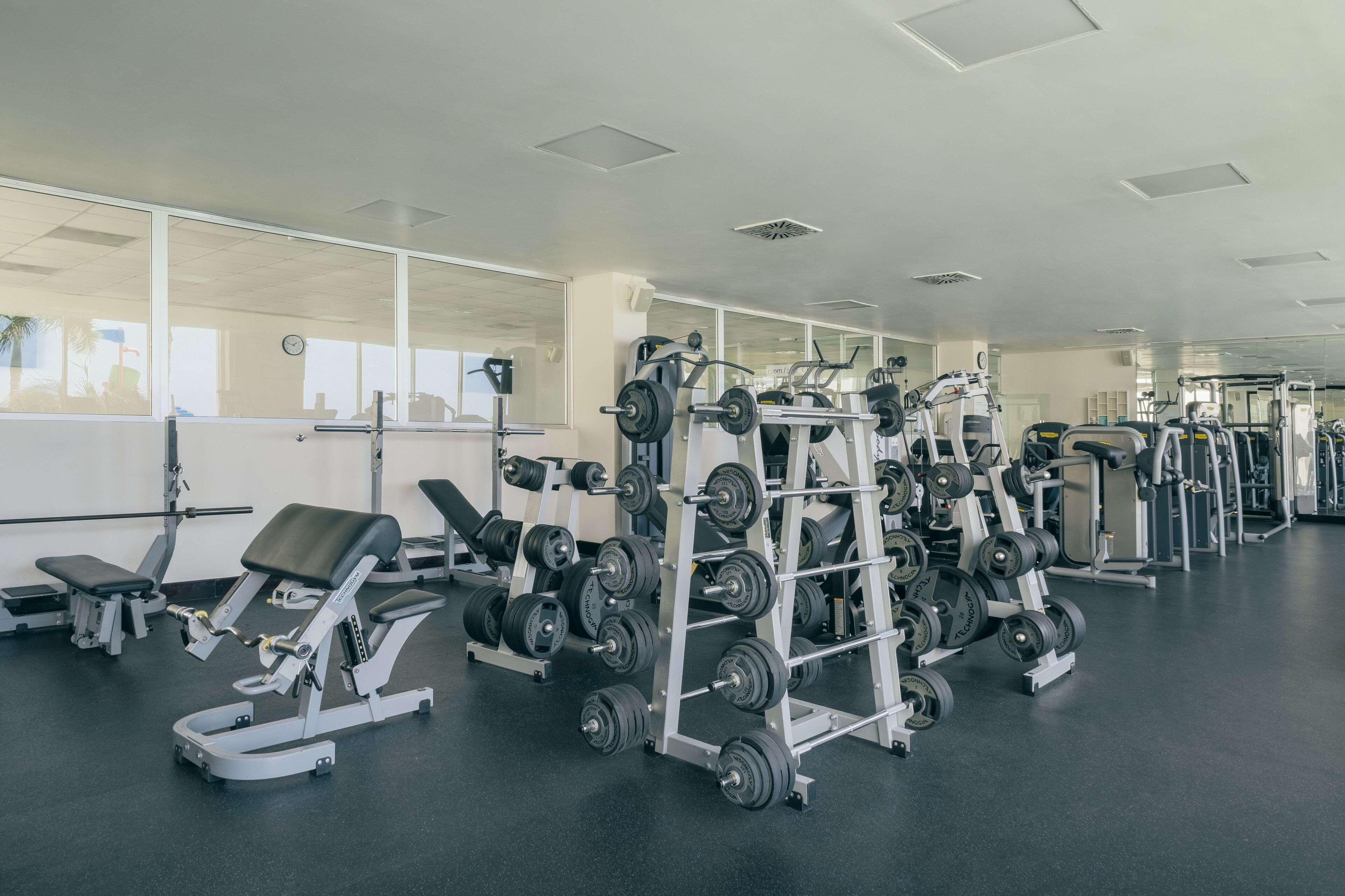 Une salle de sport équipée de matériel de musculation et de bancs.