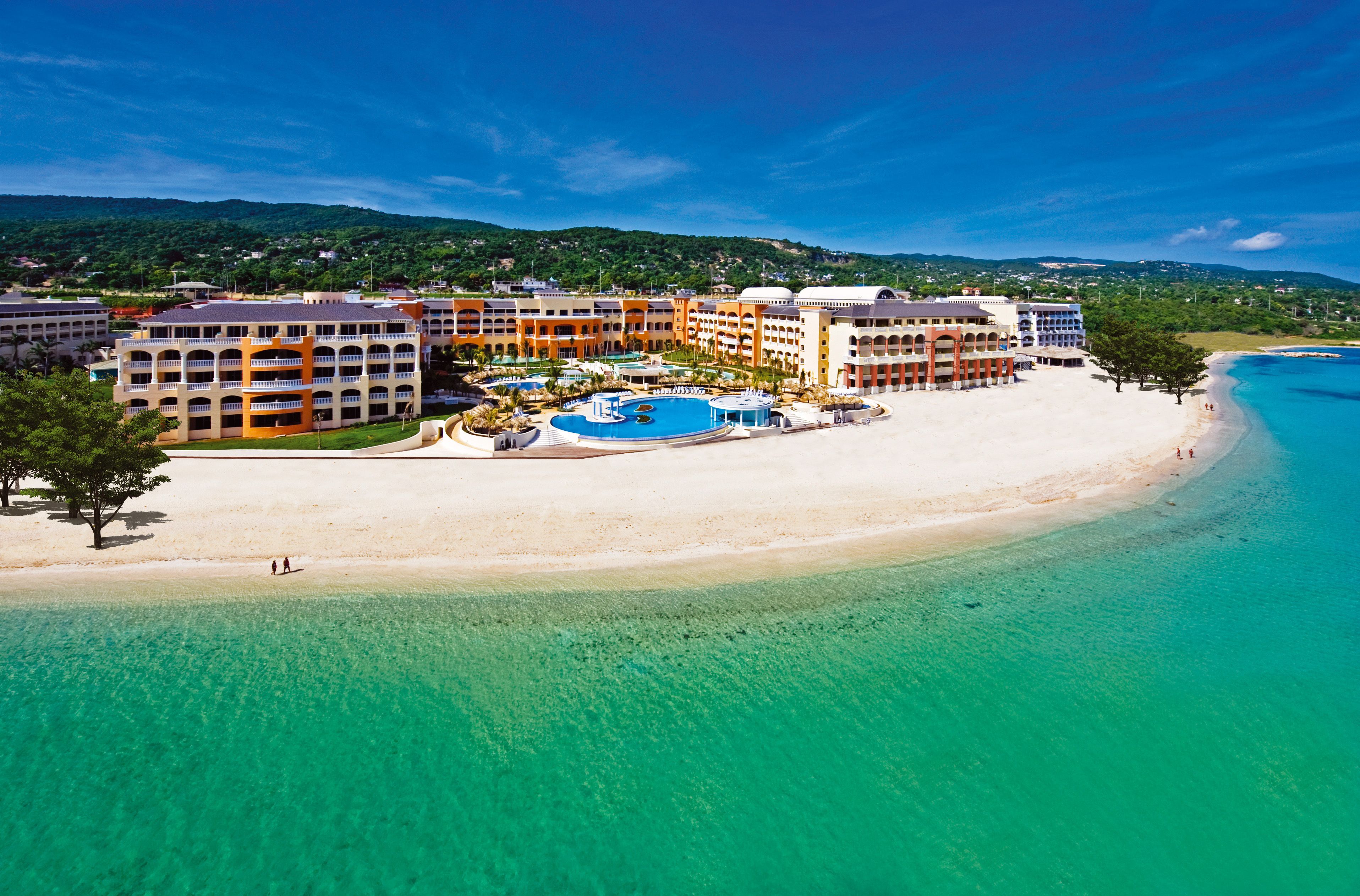 Un complexe hôtelier doté d’une plage, d’une piscine et situé au pied d’une montagne.