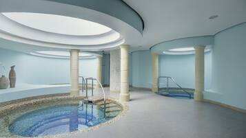 A modern indoor pool with a circular design, featuring a central water feature and a glass floor.