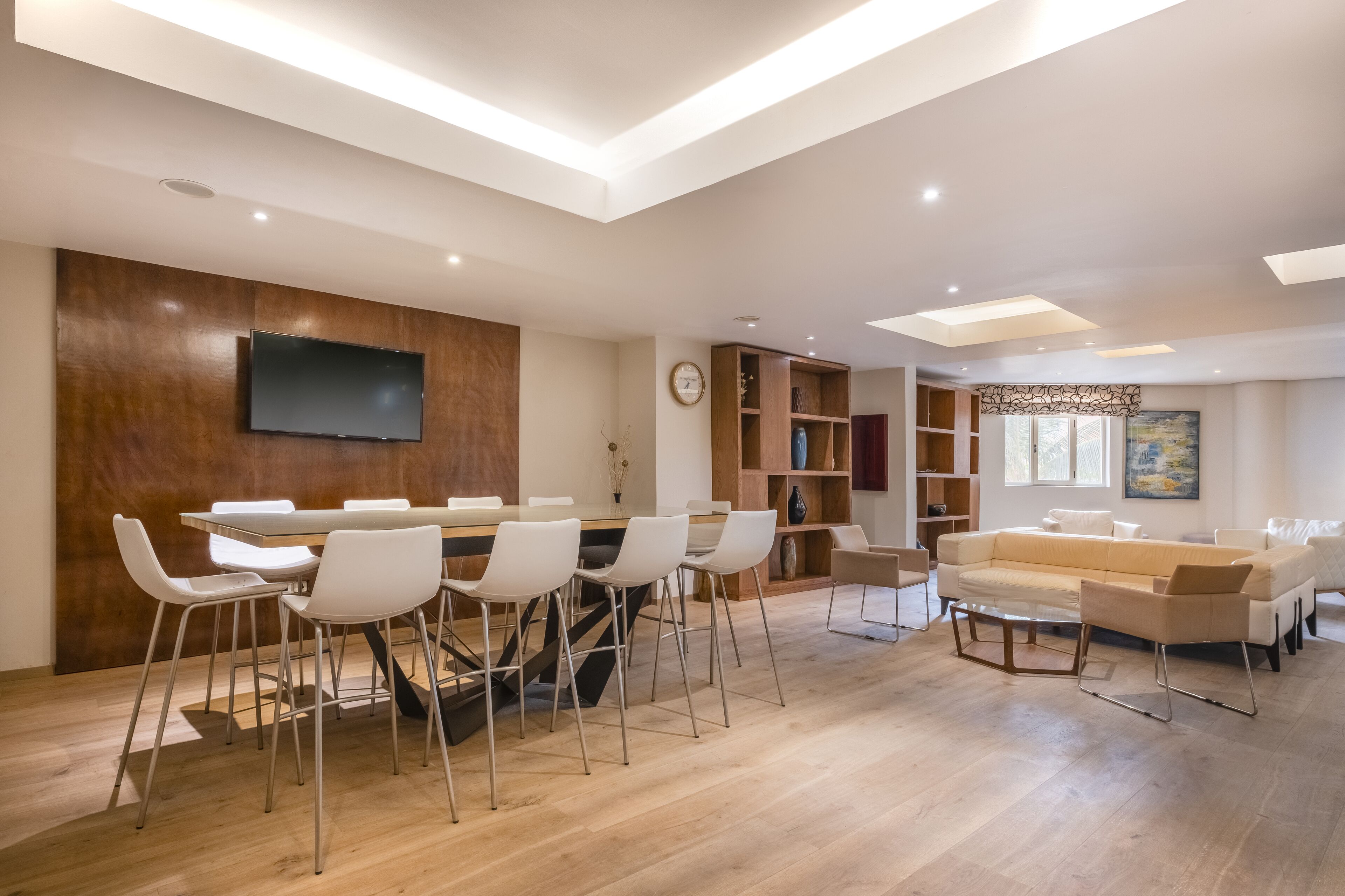 Una sala de estar moderna con comedor, paneles de madera, un televisor de pantalla plana y un sofá.