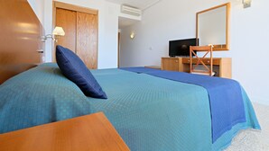 Une chambre d’hôtel bien rangée, avec un lit, un bureau et un téléviseur.