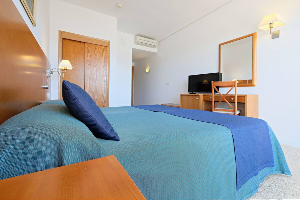A neatly arranged hotel room with a bed, a desk, and a television.