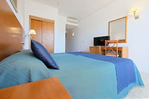A neatly arranged hotel room with a bed, a desk, and a television. - Azuline Hotel S'anfora & Fleming (Sant Antoni de Portmany)