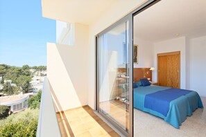 A balcony with a glass door leading to a bedroom with a bed and a nightstand. - Azuline Hotel S'anfora & Fleming (Sant Antoni de Portmany)