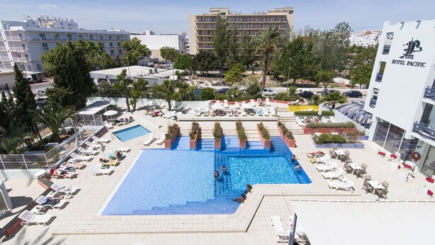 A rooftop pool area with multiple swimming pools, sun loungers, and a view of surrounding buildings. - azuLine Hotel Pacific (Sant Antoni de Portmany)