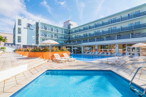 Un hôtel doté d’un espace piscine, comprenant des chaises longues et des parasols.