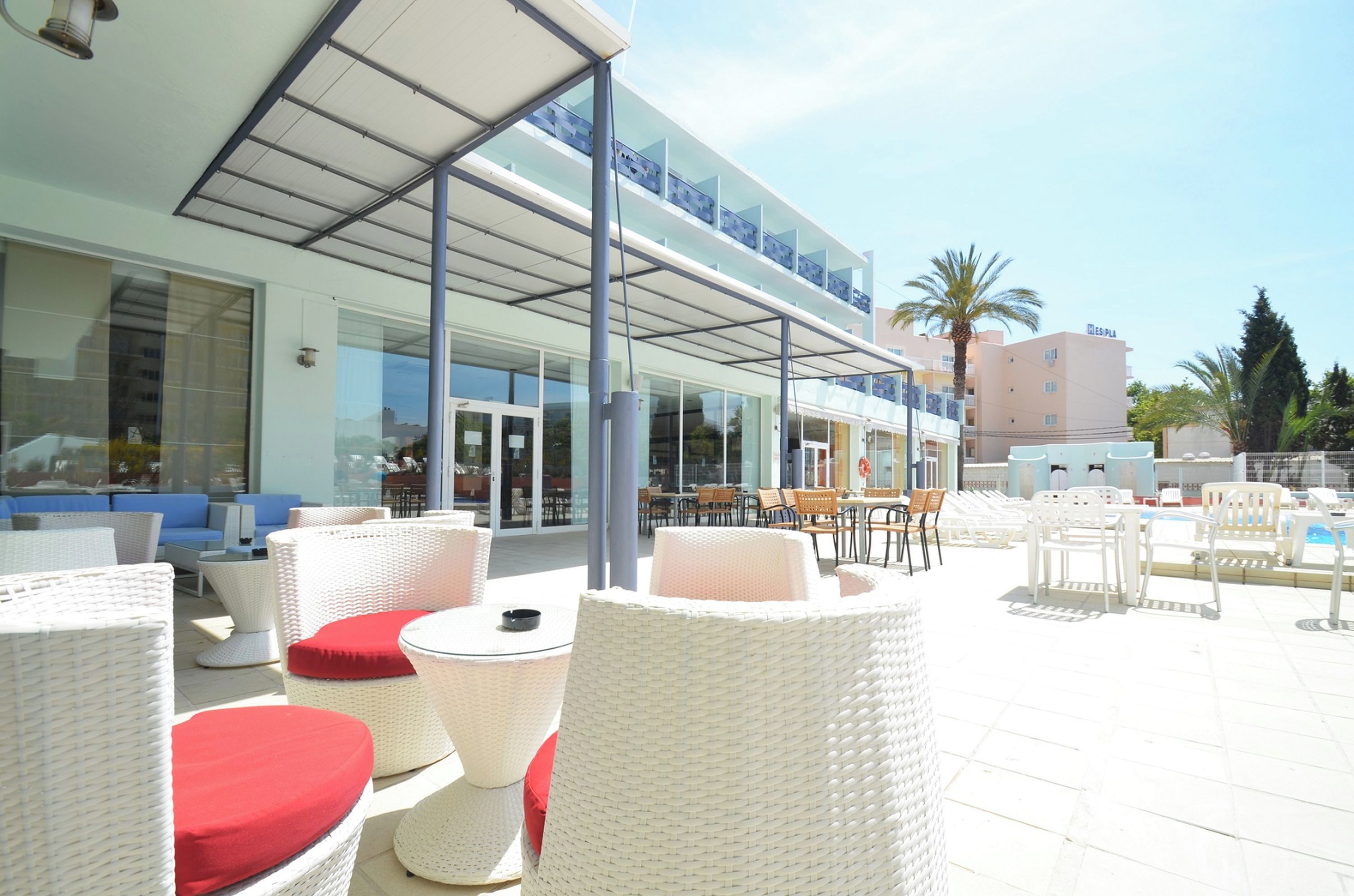An outdoor seating area with wicker furniture and a glass-enclosed building in the background.