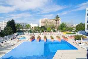 A large outdoor swimming pool with lounge chairs and sunbeds, surrounded by palm trees and buildings. - Azuline Hotel Pacific (Sant Antoni de Portmany)