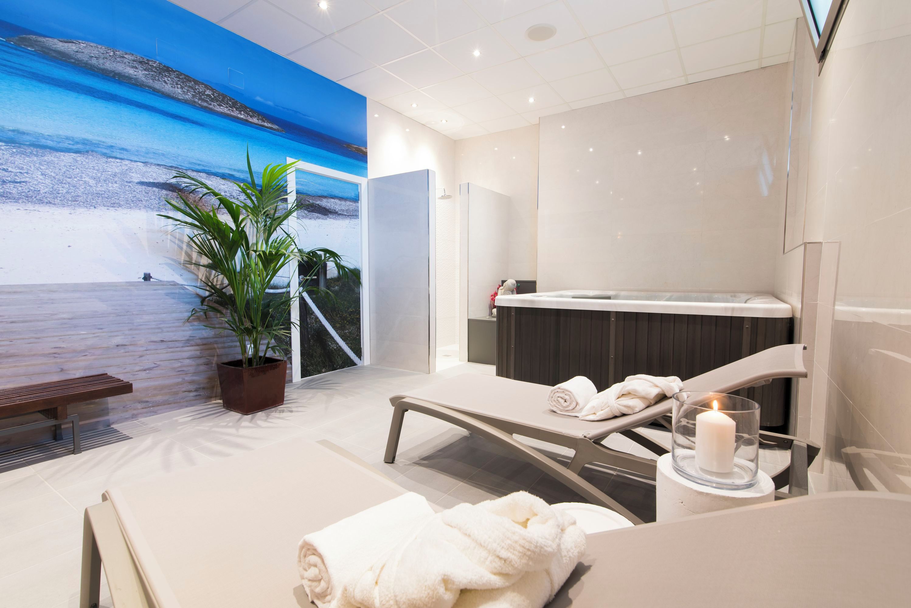 A modern spa room with a large window, a massage table, a bench, and a potted plant.