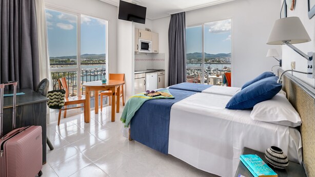 Ein Hotelzimmer mit Bett, Schreibtisch, Stuhl und Blick auf die Stadt.