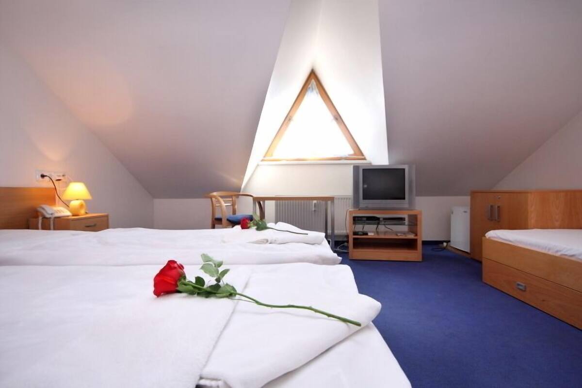 Et hotelværelse med to senge, et skrivebord, et fjernsyn og en radiator.