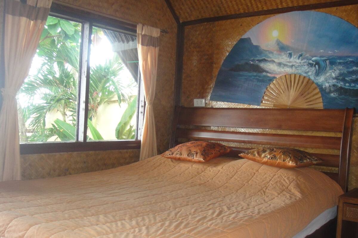 A bed with a quilt, pillows, and a headboard with a fan.