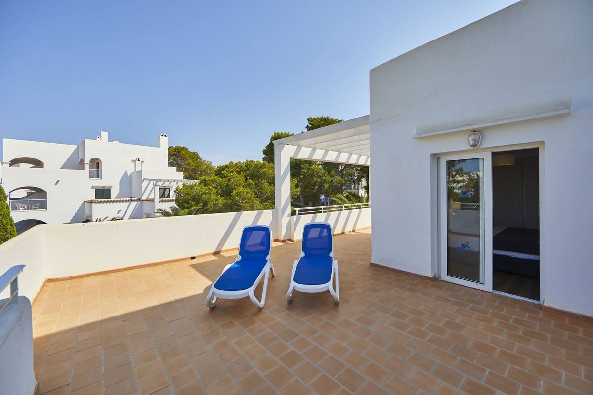 Terraza en la azotea con dos sillones azules y un área cubierta con puerta de vidrio corredera.