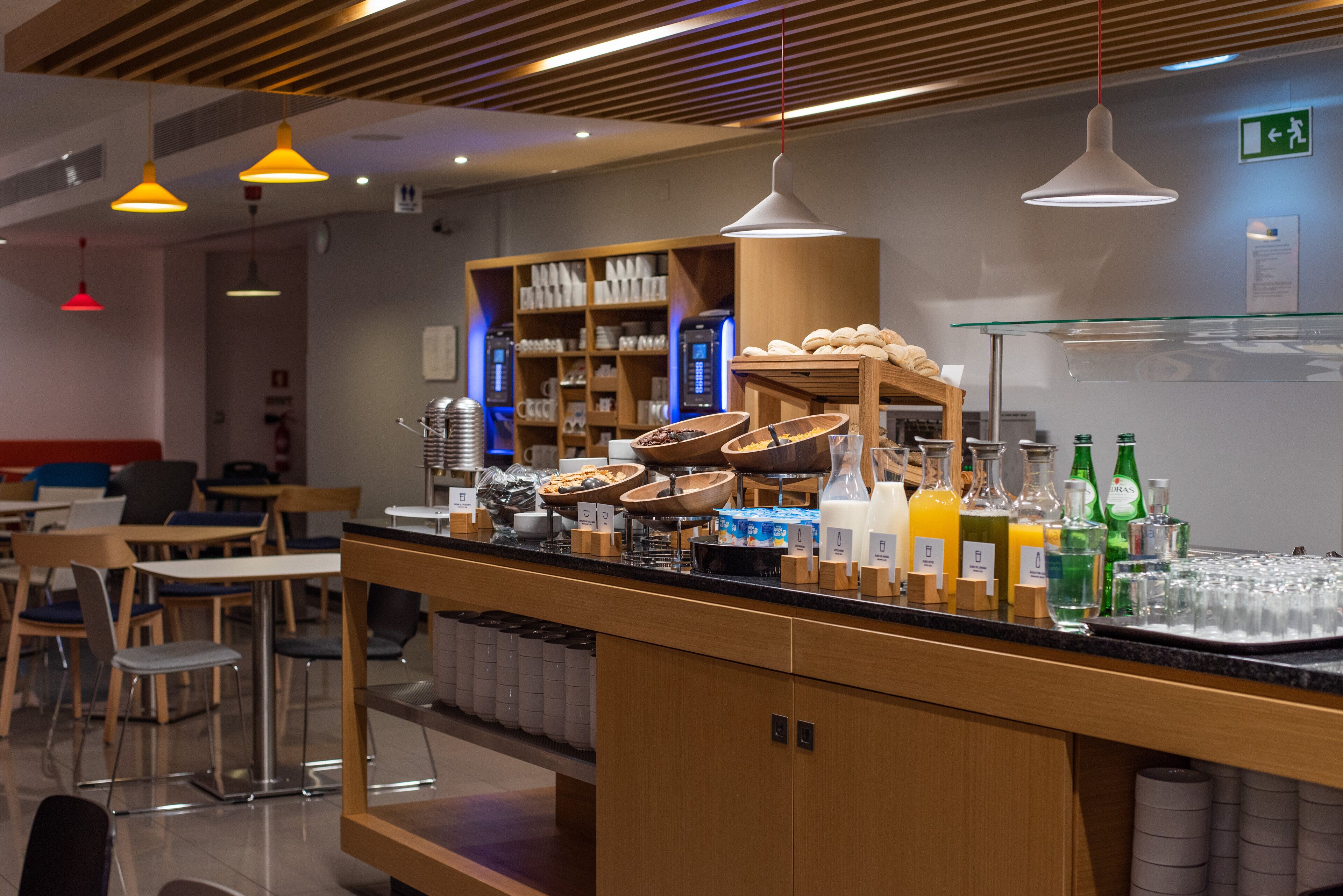 A breakfast bar with various food items and beverages, wooden furniture, and a modern interior design.