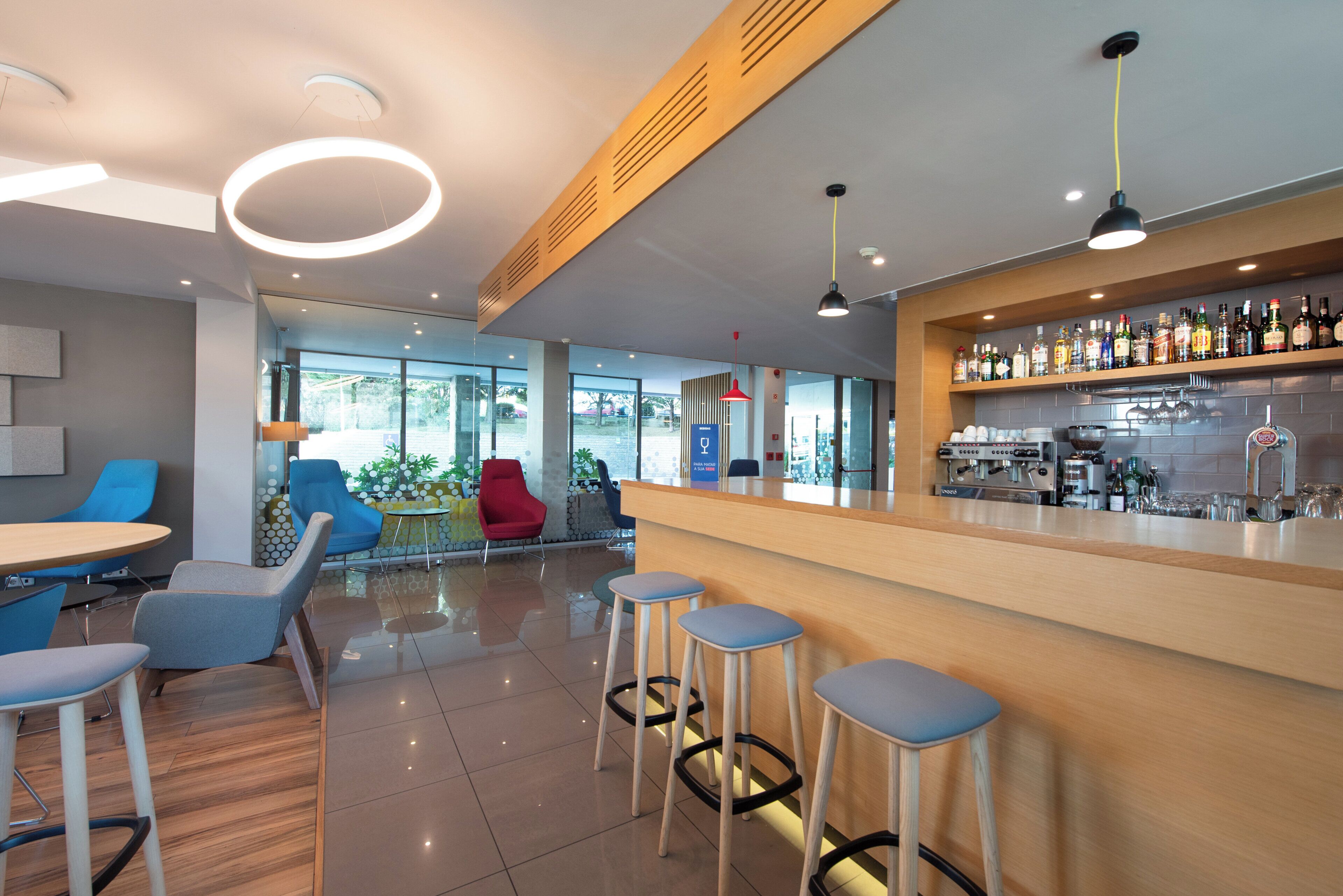 A modern bar area with stools, a bar counter, and a variety of bottles.