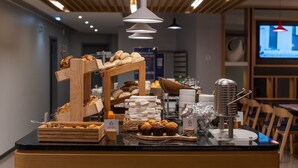A breakfast buffet with various pastries and bread, wooden display stands, and a modern ceiling design.