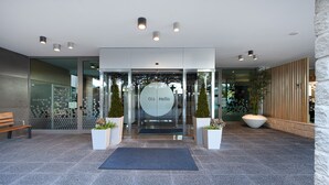 Una entrada moderna con puerta de vidrio, un banco y plantas en macetas.