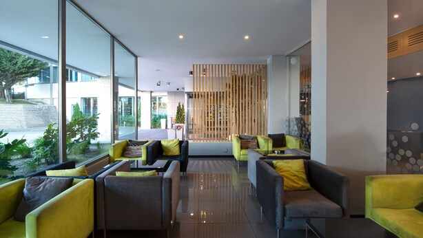 Un vestíbulo moderno con zonas de estar, ventanas amplias y un panel decorativo de madera.