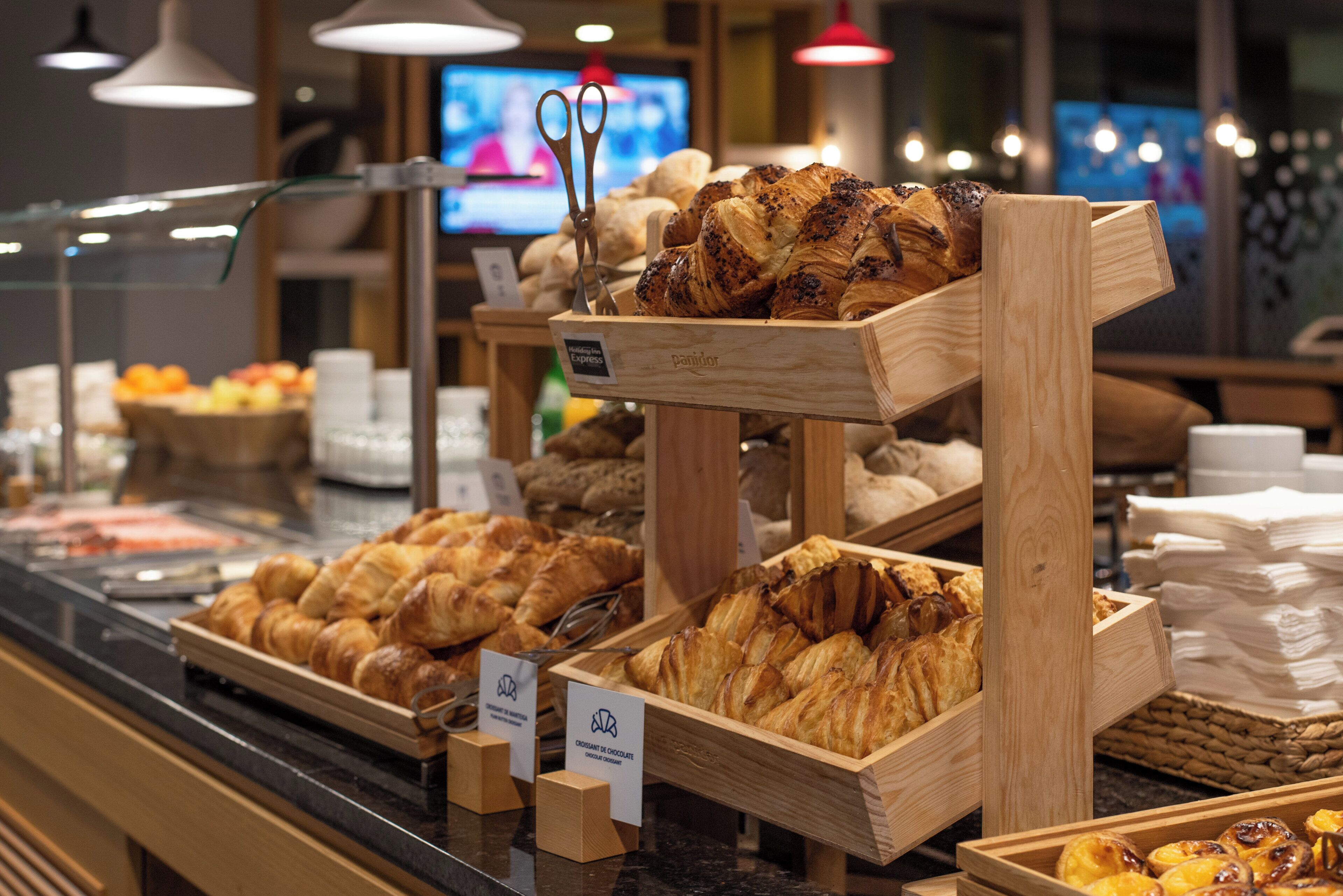 Vitrine de uma padaria com diversos produtos de panificação e um aviso indicando Holiday Inn Express.