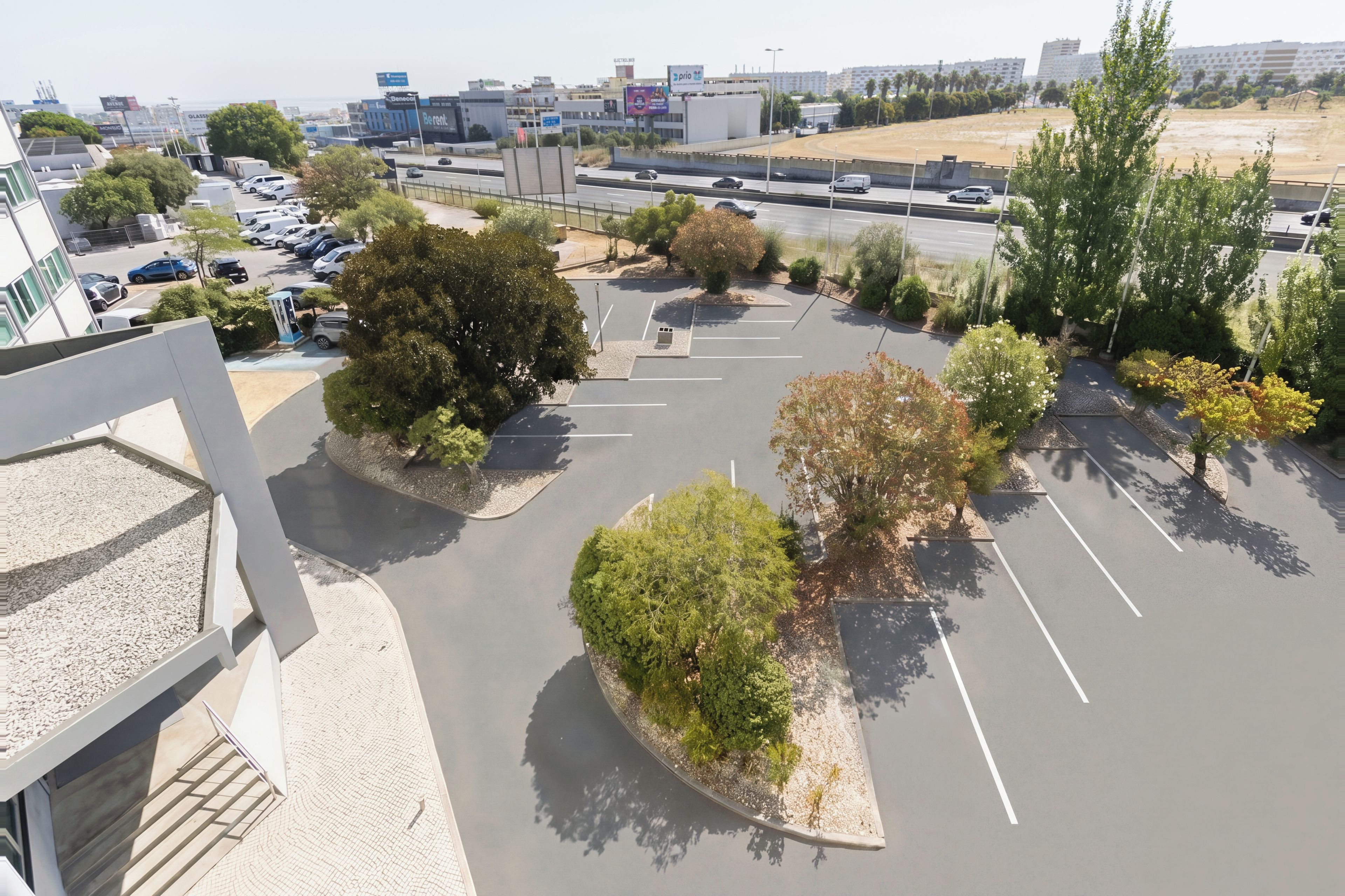 A parking lot with multiple rows of parking spaces, surrounded by landscaped areas with trees and shrubs.
