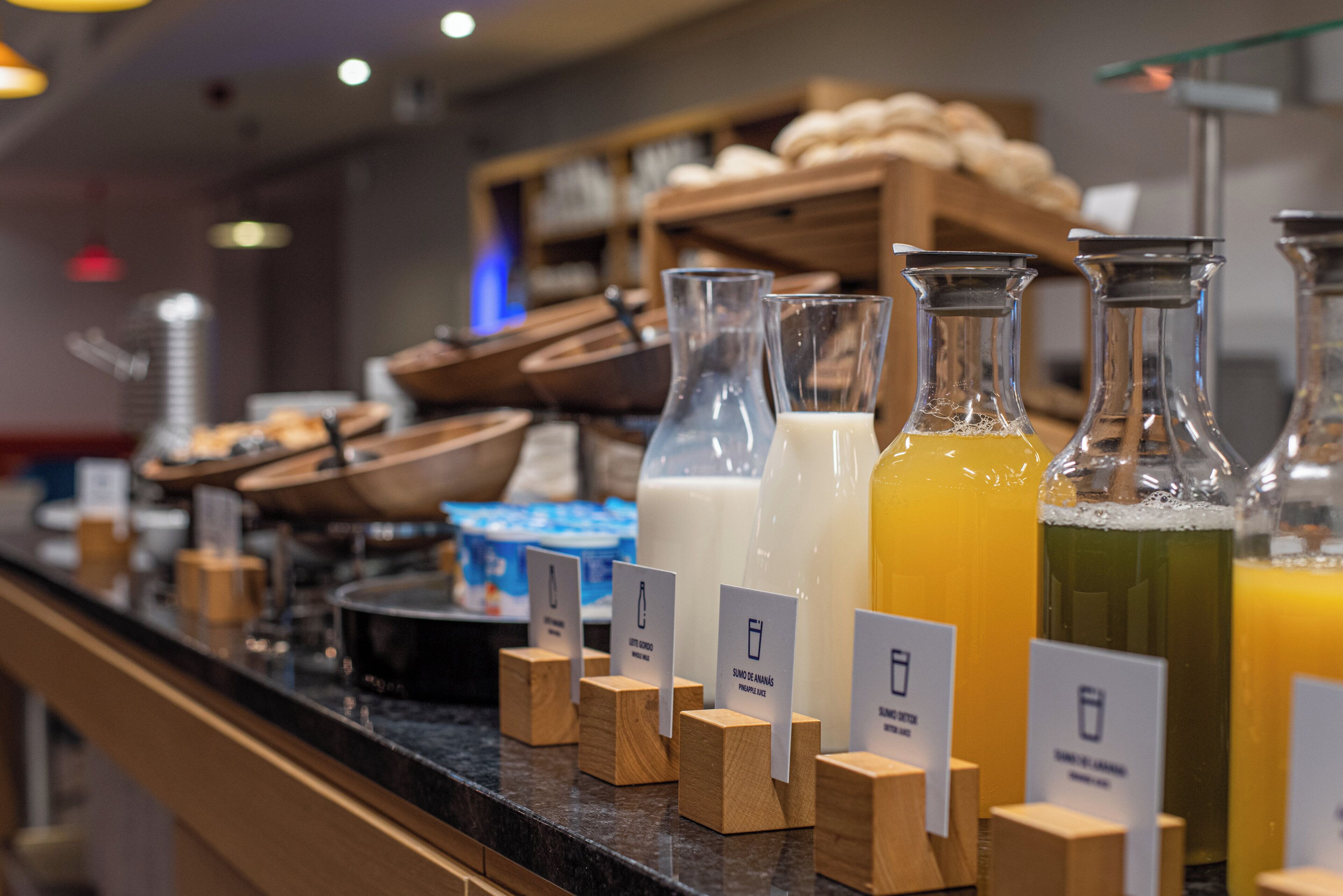 A beverage station with various drinks and wooden blocks with labels.