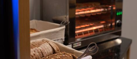 Mostrador de panadería con panes variados y una rebanadora.