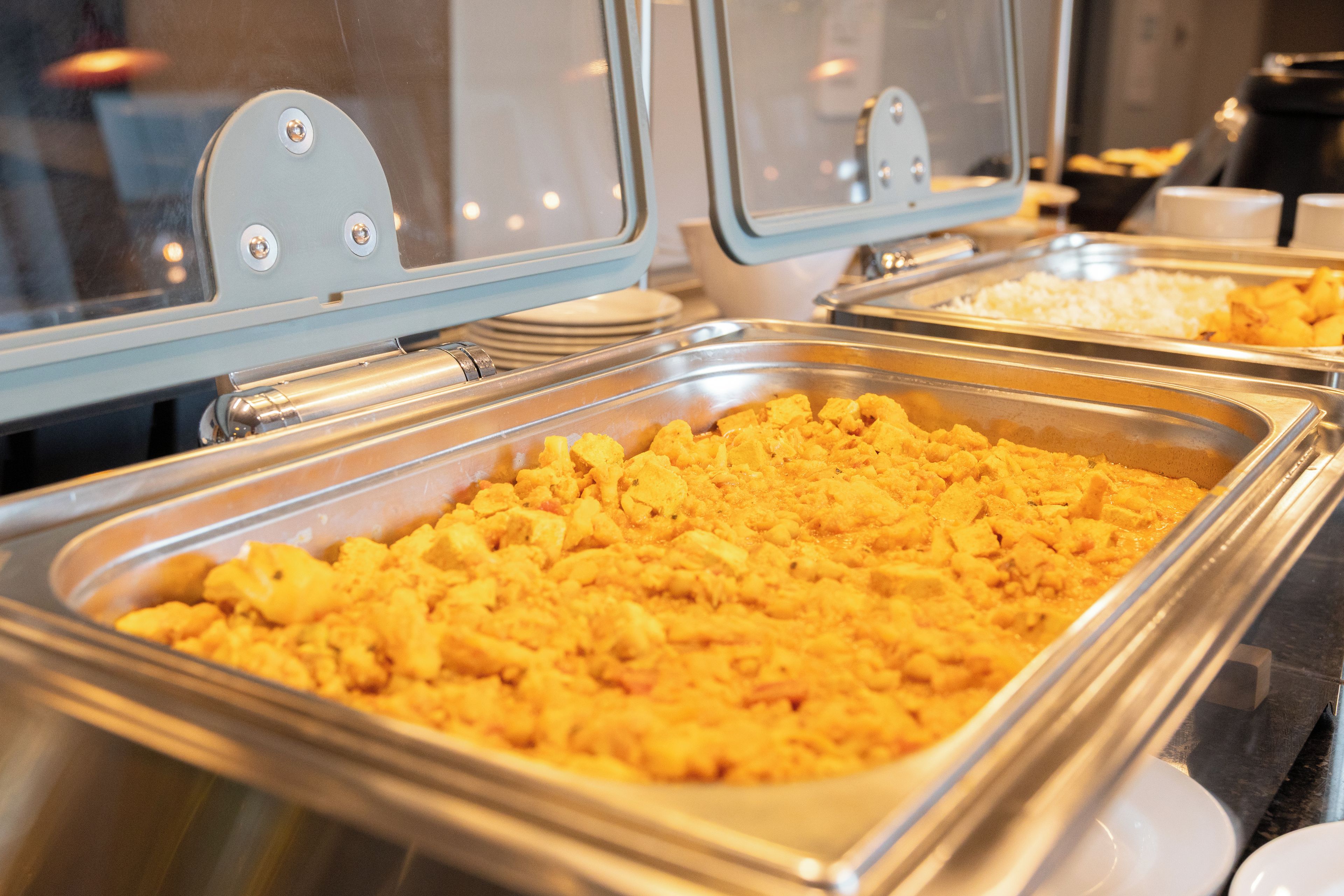 Un buffet proposant divers plats présentés dans des plateaux de service en métal.