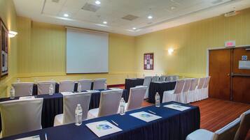 Une salle de conférence avec des tables disposées pour une réunion, équipée de bouteilles d’eau et de plaques nominatives.