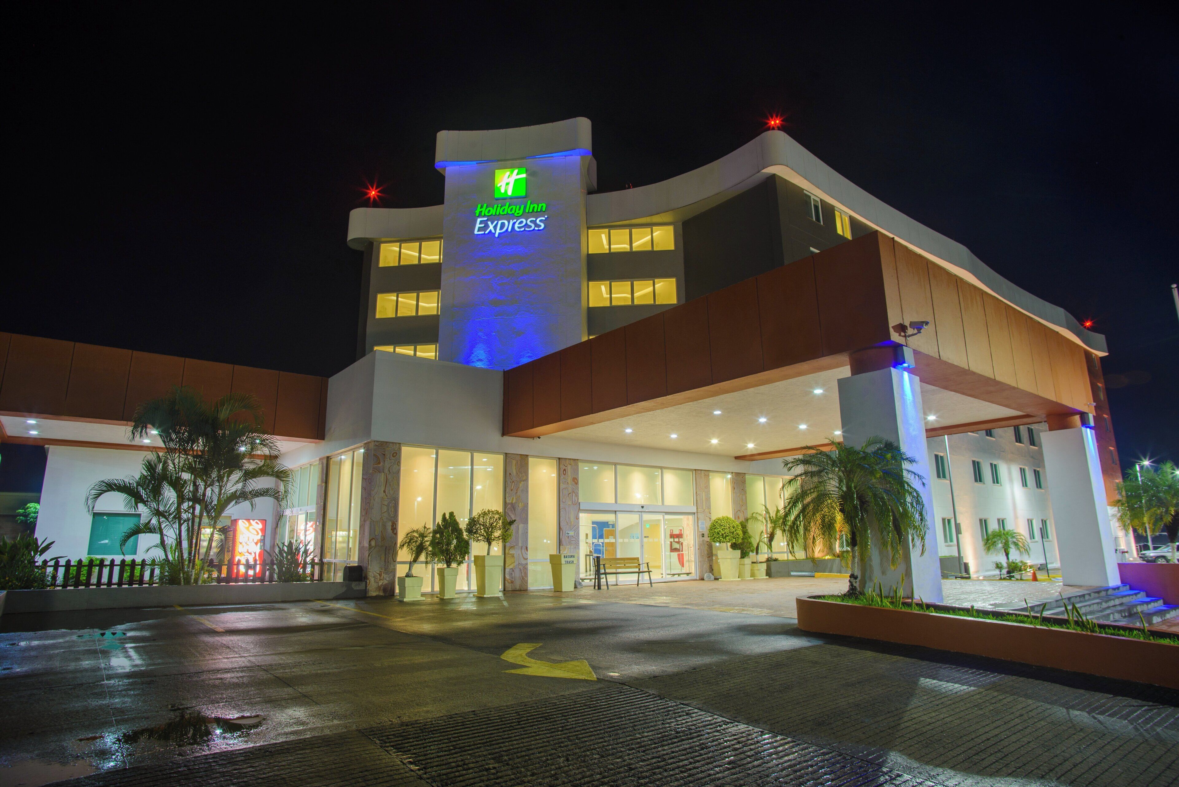 Een Holiday Inn Express gebouw met een opvallend bord, grote ramen en een goed verlichte ingang.