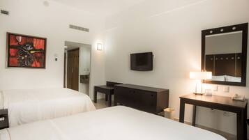 Habitación de hotel con dos camas, un escritorio, una cómoda, televisor, espejo y un cuadro en la pared.