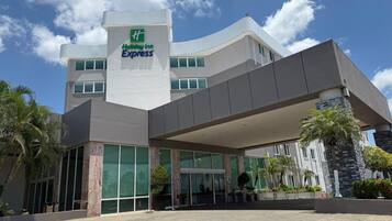 Un hotel Holiday Inn Express con diseño moderno, que cuenta con amplios ventanales y una zona de entrada cubierta.