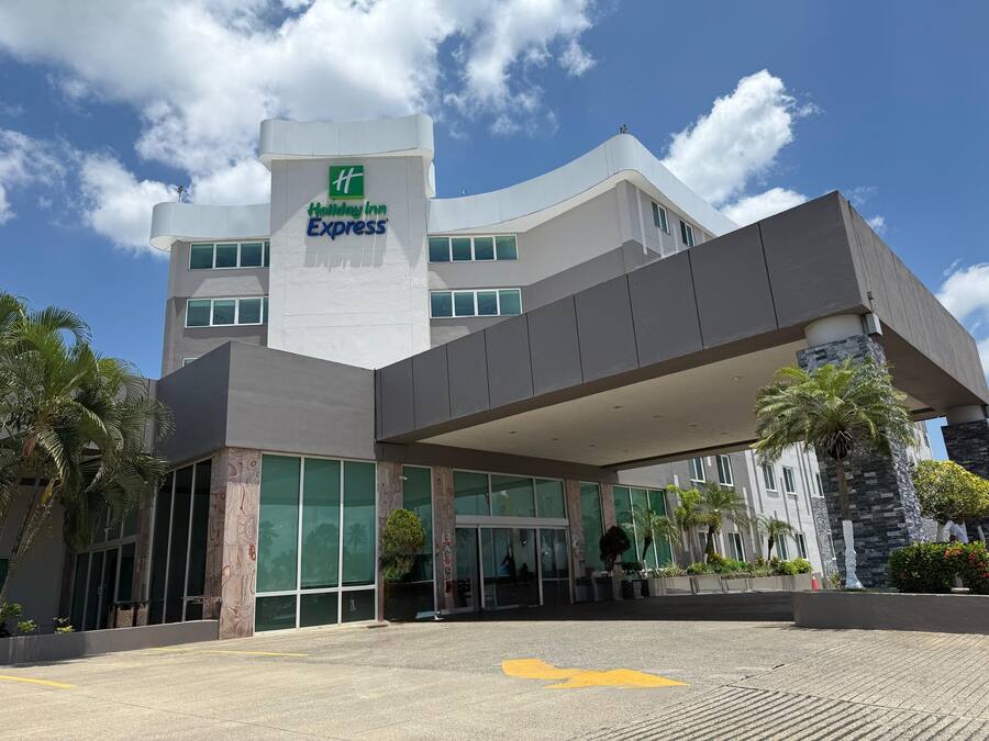 Un hotel Holiday Inn Express con diseño moderno, que cuenta con amplios ventanales y una zona de entrada cubierta.