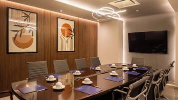 A conference room with a long table, chairs, and a large screen.