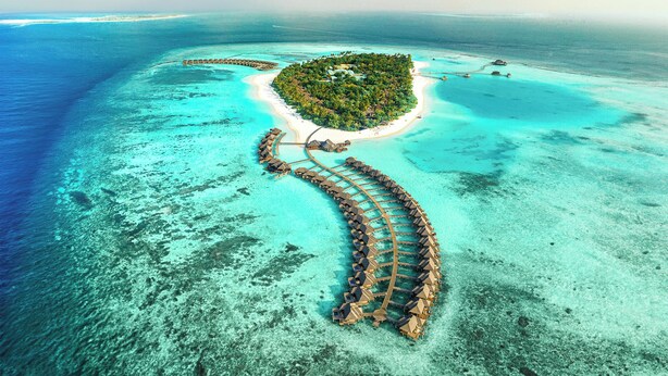 An aerial view of a tropical island resort with overwater bungalows connected by a wooden walkway. - Sun Siyam Iru Fushi (Iru Fushi)