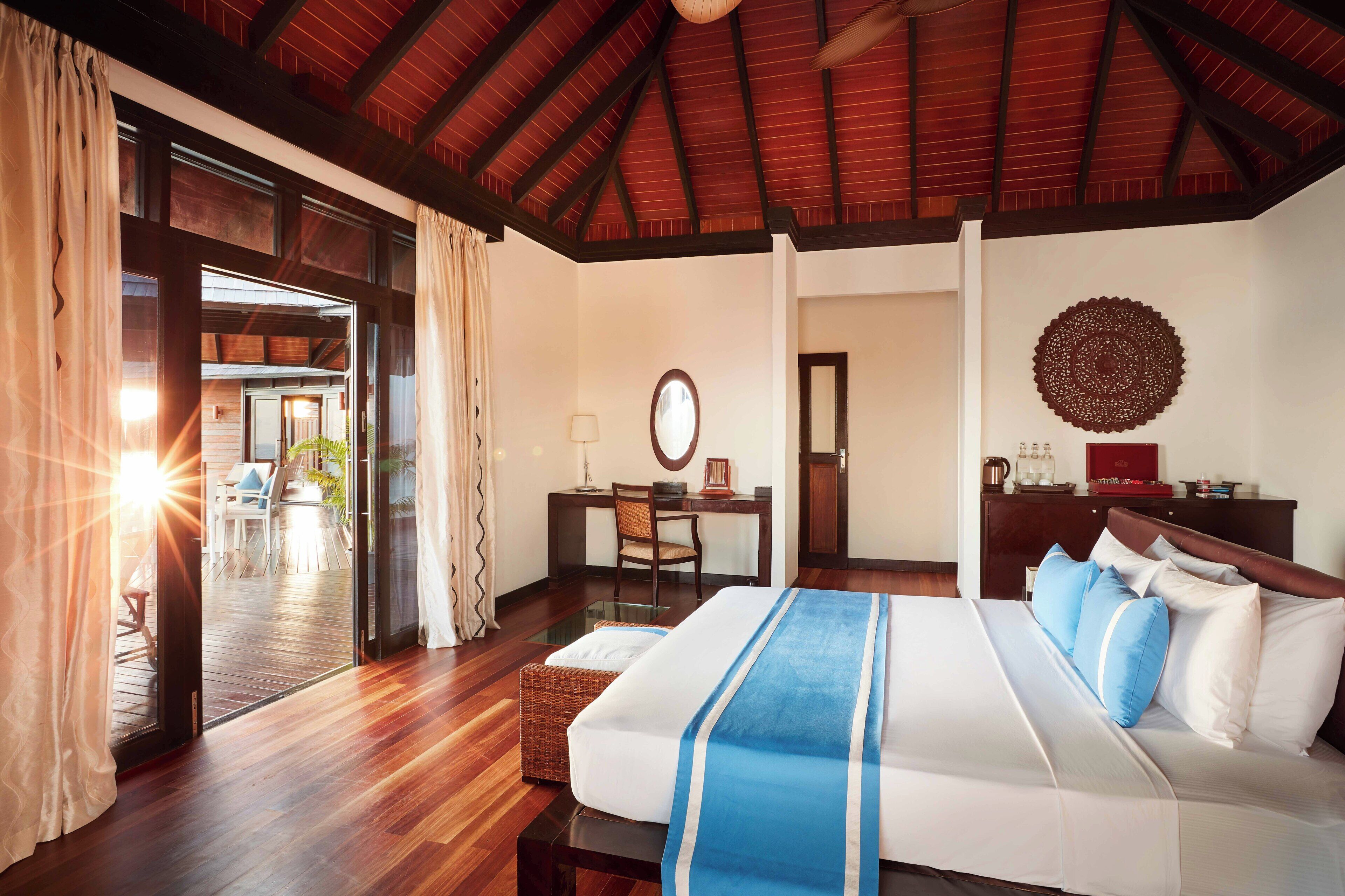 A hotel room with a large bed, a desk, and a view of the outdoor area.