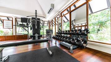 Une salle de sport équipée de machines d’exercice, d’un banc et d’haltères.