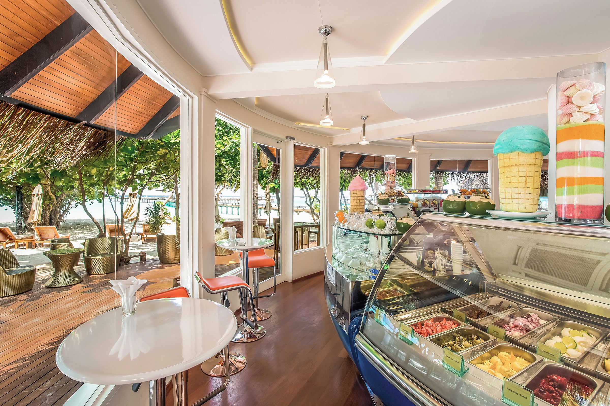A restaurant with outdoor seating, a dessert display, and a view of the beach.