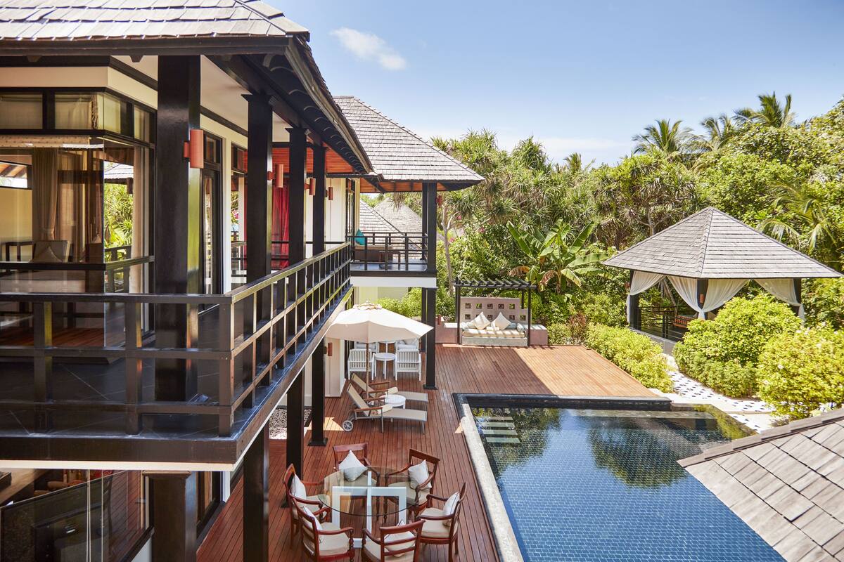 A resort with a pool, outdoor seating, and lush greenery.