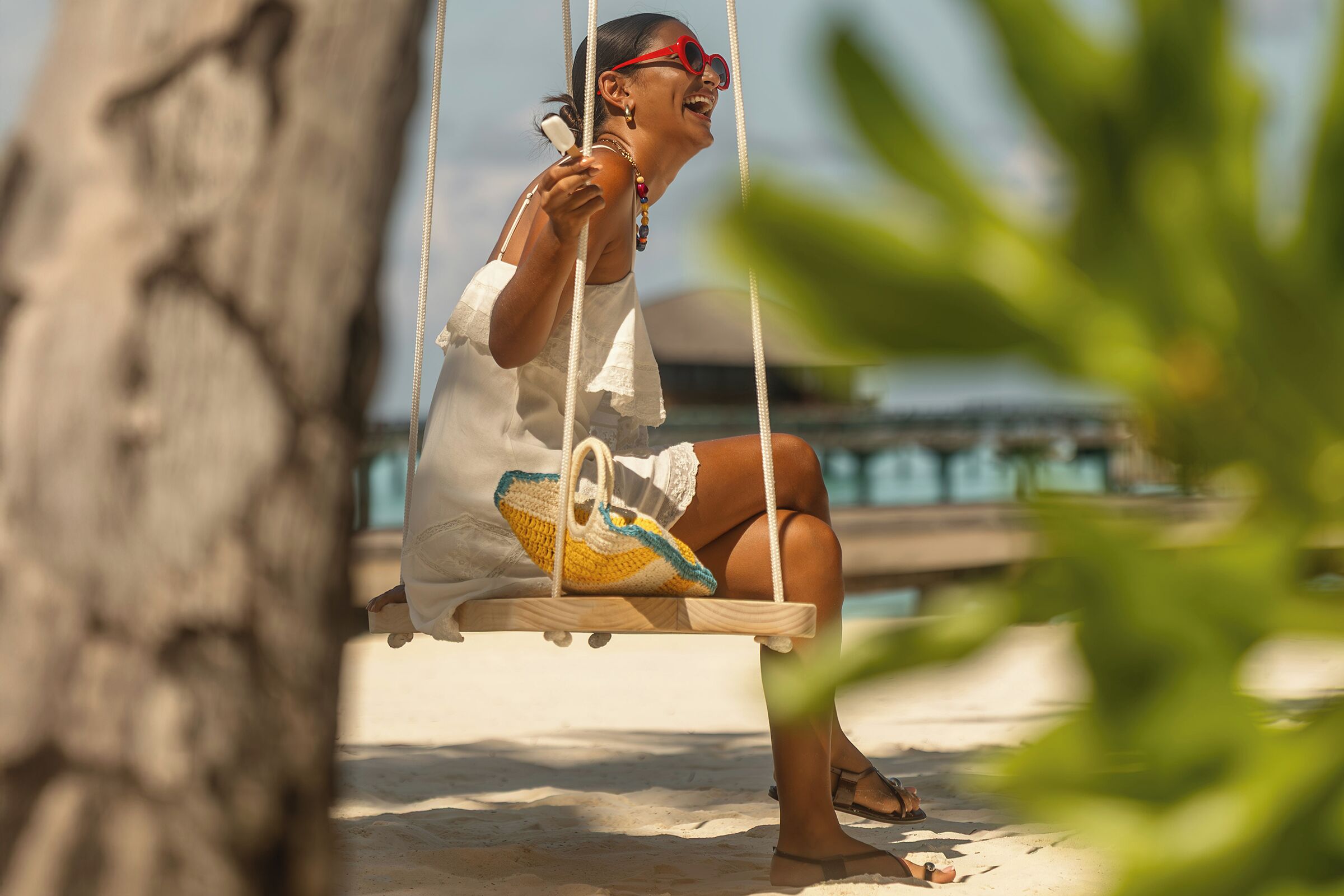 A person sitting on a swing with a beach view in the background.