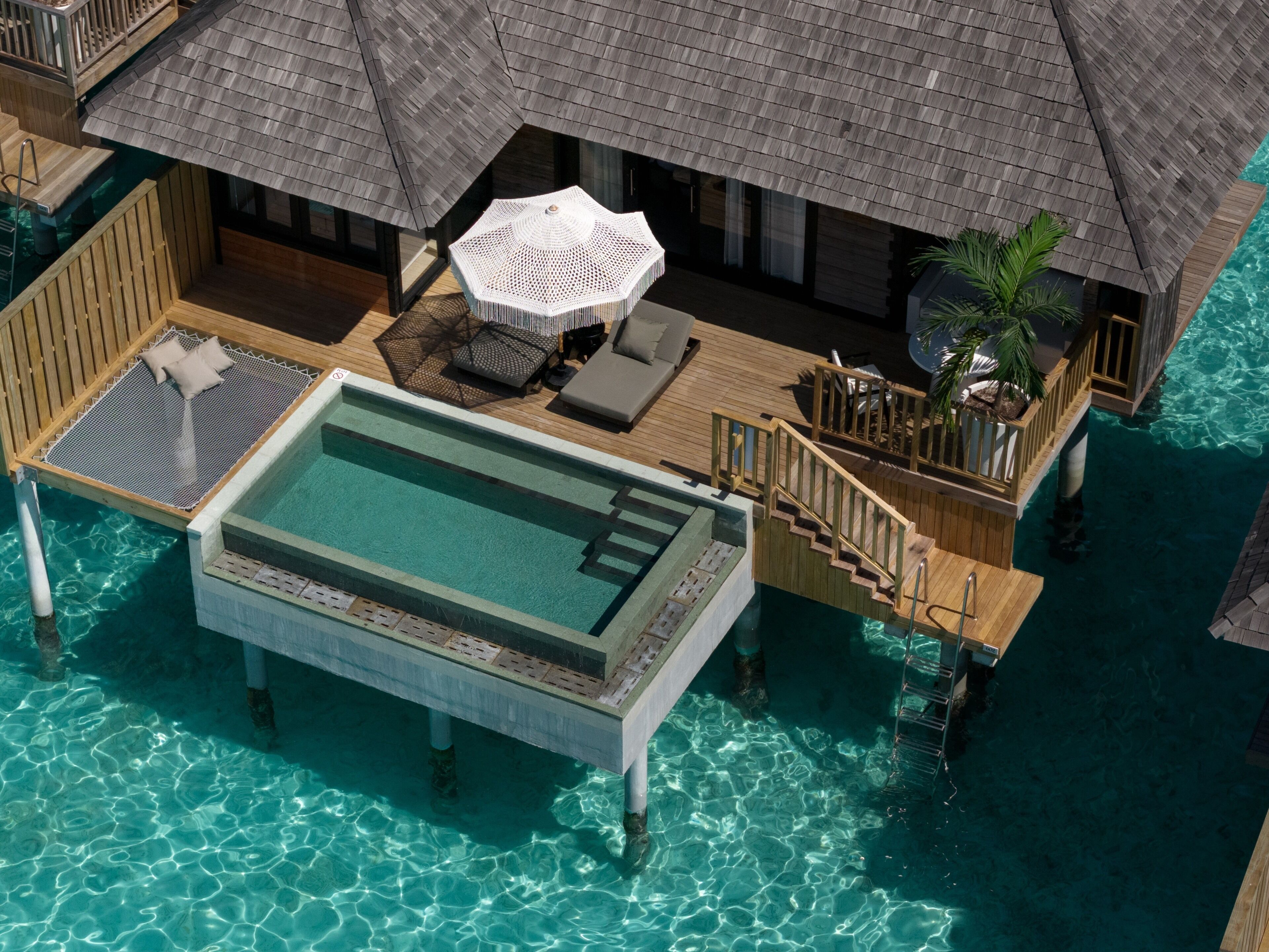 Bungalows sobre el agua con piscina, zona de estar y terraza de madera.