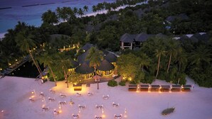 An aerial view of a resort with overwater bungalows, a beach with lounge chairs, and a pool area. - Sun Siyam Iru Fushi (Iru Fushi)