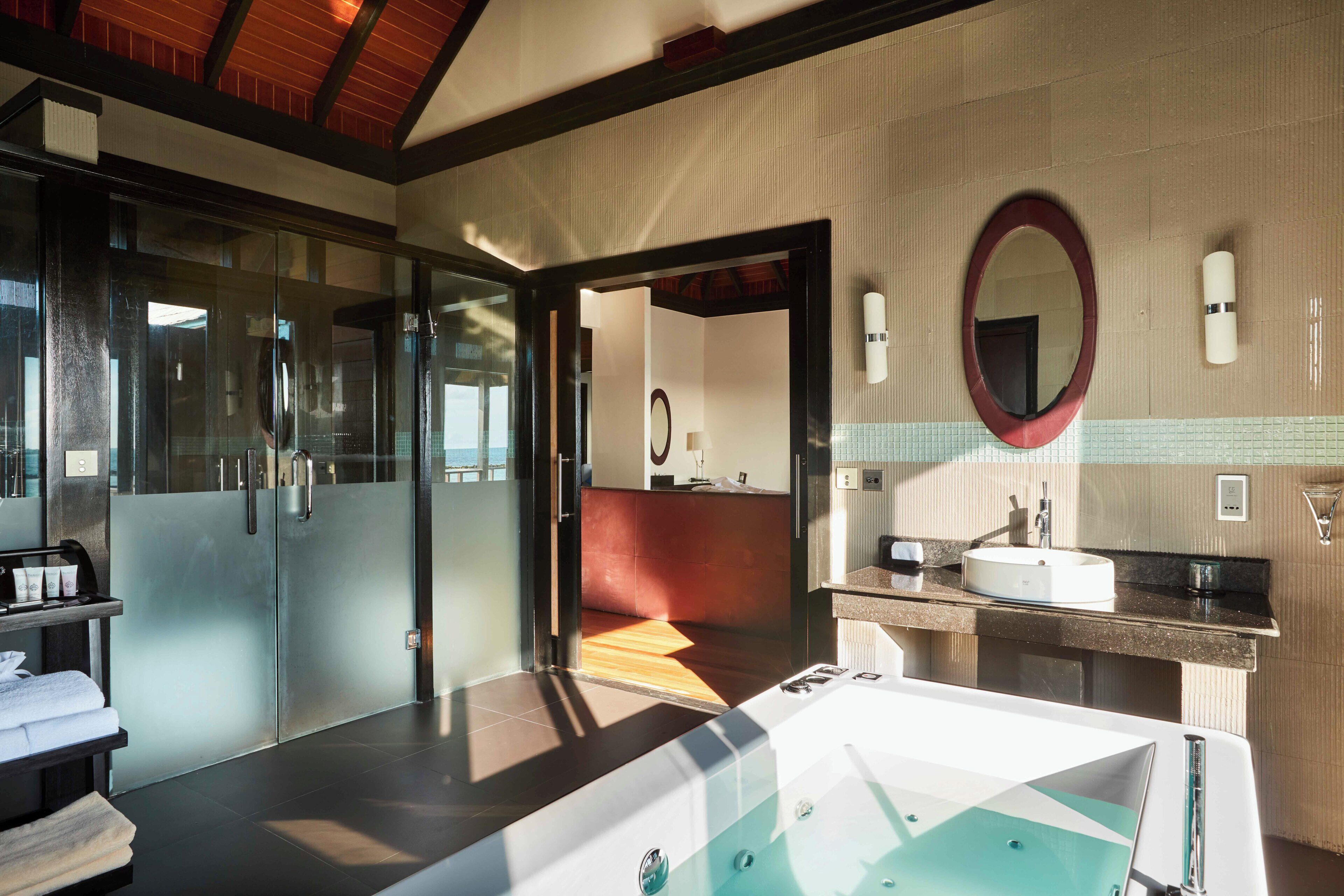 Ein modernes Badezimmer mit Duschkabine aus Glas, einer großzügigen Badewanne, einem Waschtisch und einem Spiegel.